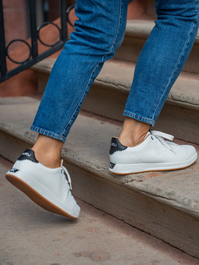 A man wearing ROAM Sneakers in New-BrightWhite-JetBlack walking down stairs.