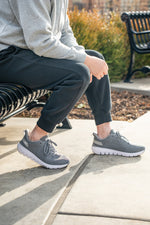 Man sitting on a bench wearing KURU Footwear's FLEX Via men's sneakers
