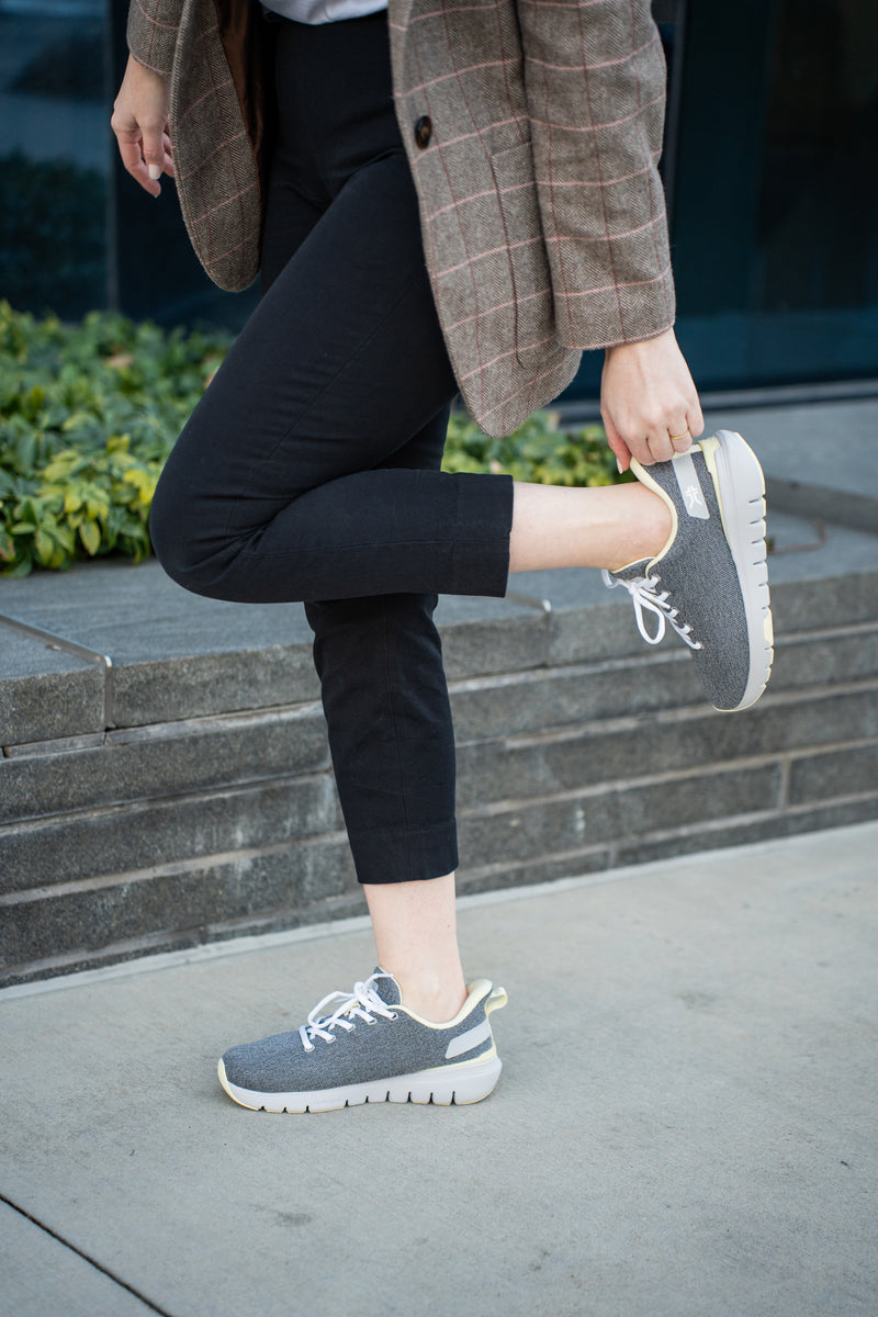 Woman showcasing her Dove Gray-Pale Lime FLEX Via sneakers by KURU Footwear while walking on the street in profile