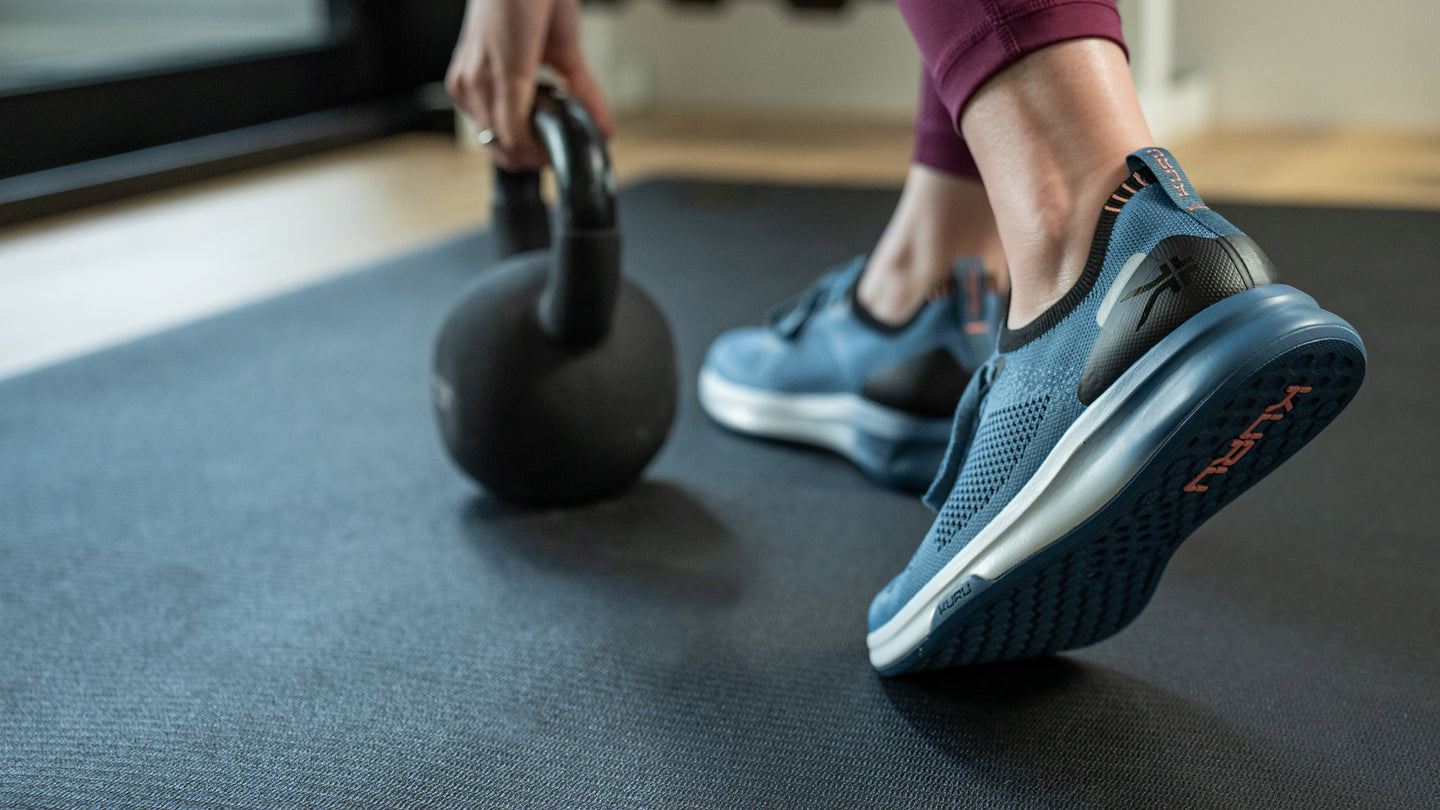 Woman working out using a kettlebell, wearing KURU Footwear’s FLUX shoes for alleviating foot pain.