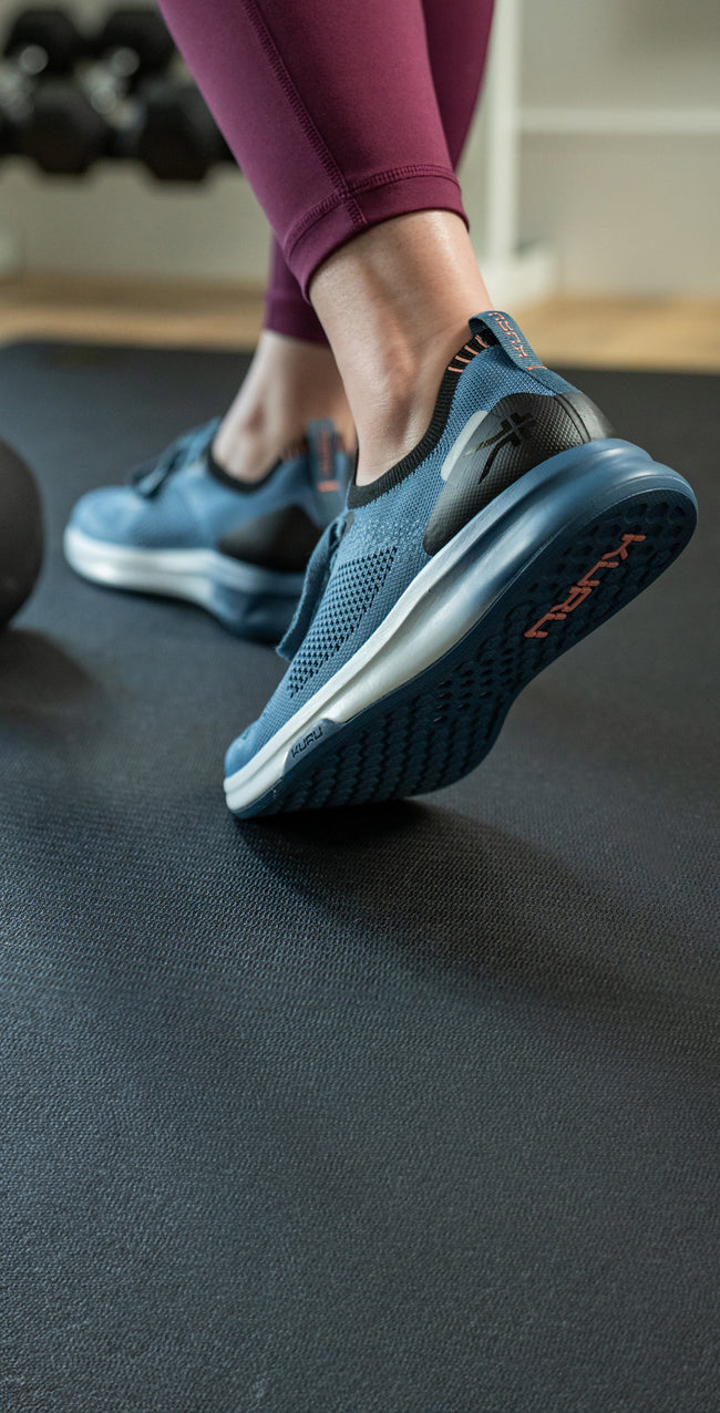 Woman working out using a kettlebell, wearing KURU Footwear’s FLUX shoes for alleviating foot pain.
