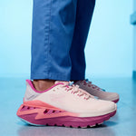 Pink and purple shoes worn with blue pants on a light blue background