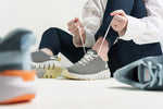 KURU Footwear's FLEX Via sneaker. Seated woman tying shoelaces, showcasing the worn shoe