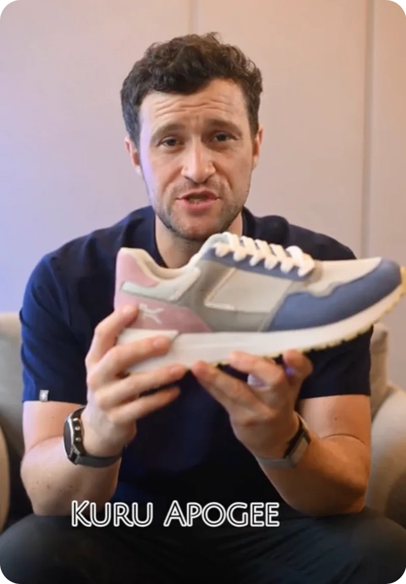 Reviewer holding KURU APOGEE sneaker, highlighting comfort features for plantar fasciitis relief.