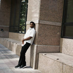 Man wearing KURU ATOM 2 Men's Athletic Sneaker in Jet Black leaning against a city building.