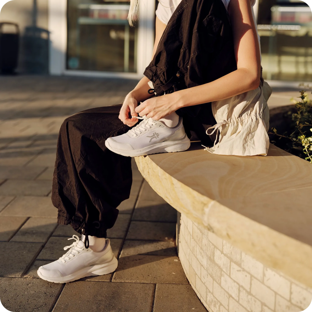 Person tying the laces of KURU DRAFT Rento shoes in Bright White for all-day comfort.