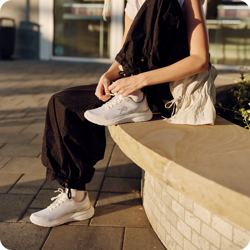 Person tying the laces of KURU DRAFT Rento shoes in Bright White for all-day comfort.