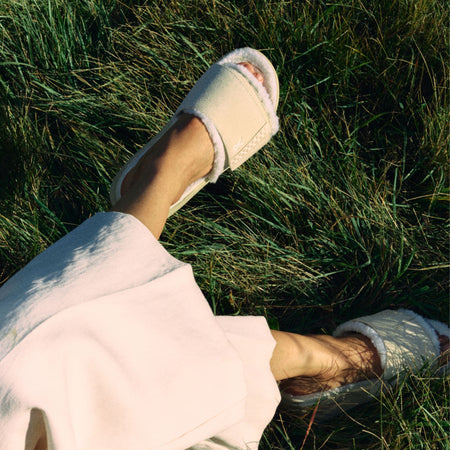 Close-up of KURU MOMENT Women's Cozy Slides in Ashwood-Winter Cream worn while lying in the grass.