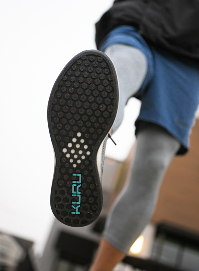 Man showing the detail on the bottom KURU Footwear's FLUX shoes for alleviating foot pain