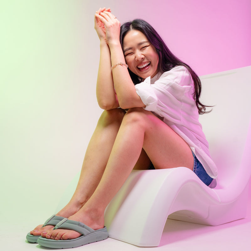Woman sitting on a white chair with a colorful gradient background