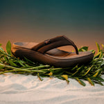 Brown sandals on a bed of green leaves with a blurred natural background