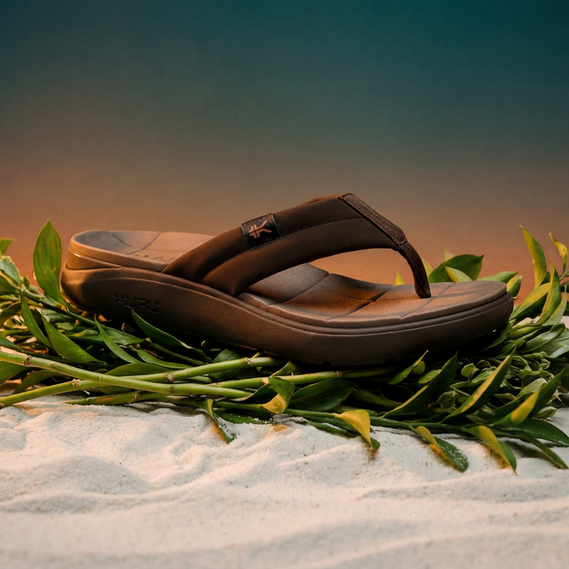 Brown sandals on a bed of green leaves with a blurred natural background
