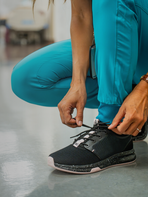Woman tying KURU Footwear ATOM Women's Athletic Sneaker in color JetBlack-MistyLilac