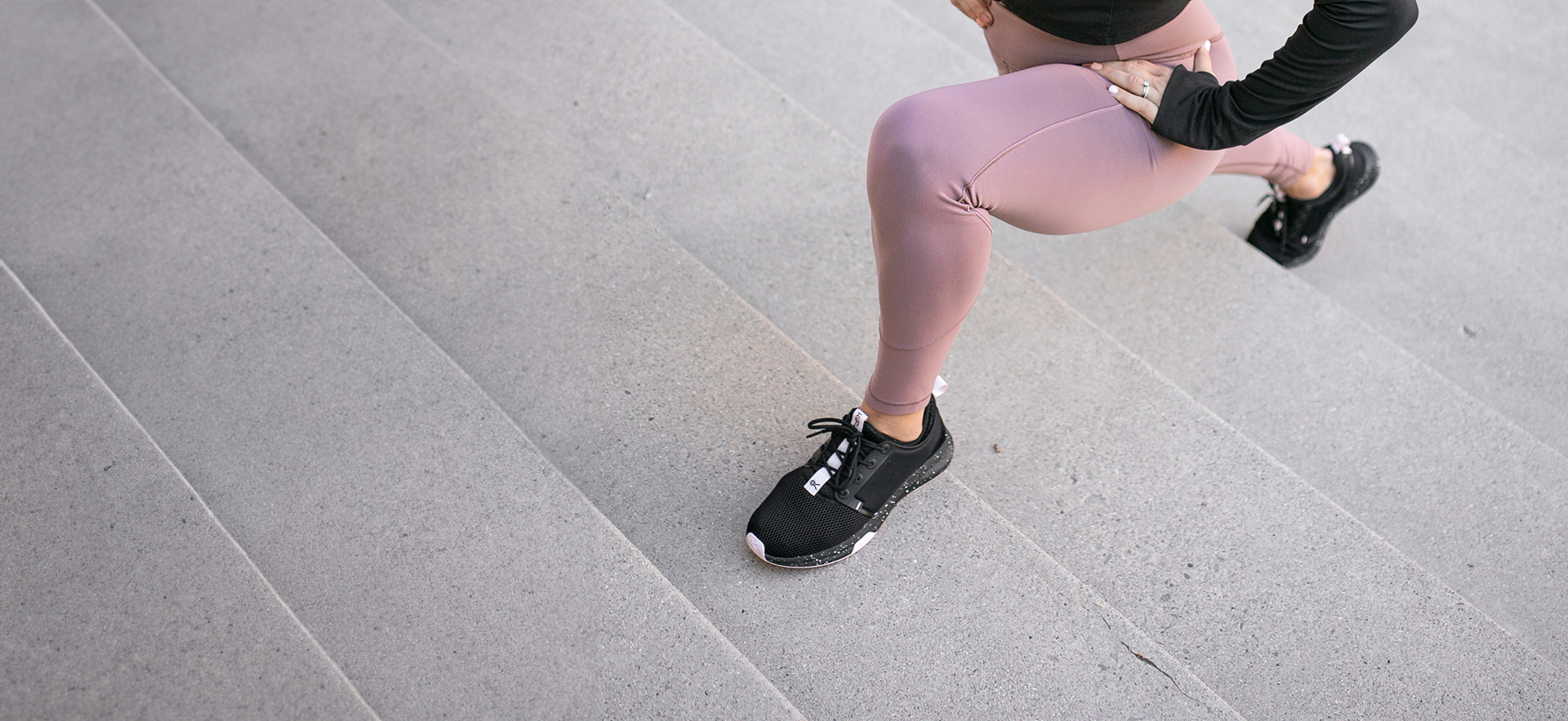 Woman exercising and stretching her legs on stair steps, wearing comfortable shoes by KURU Footwear.